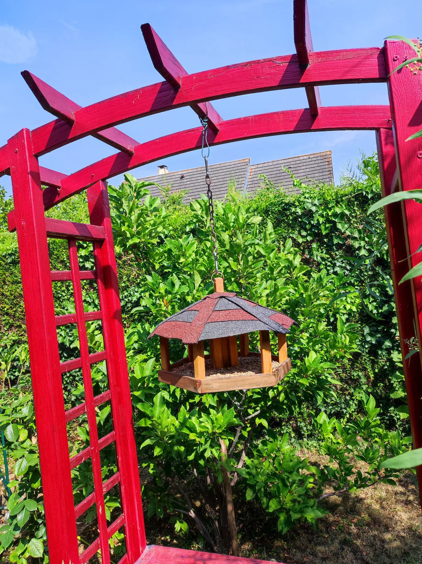 Mangeoire La Suspendue installée sous une pergola rouge